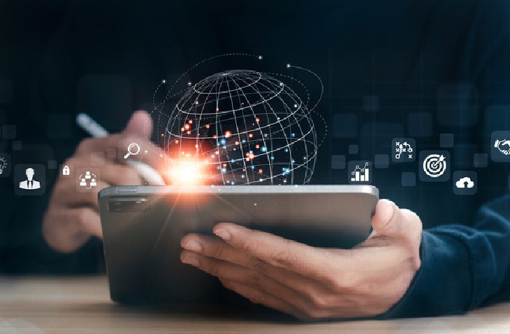 hands holding tablet with digital globe and marketing icons floating above screen