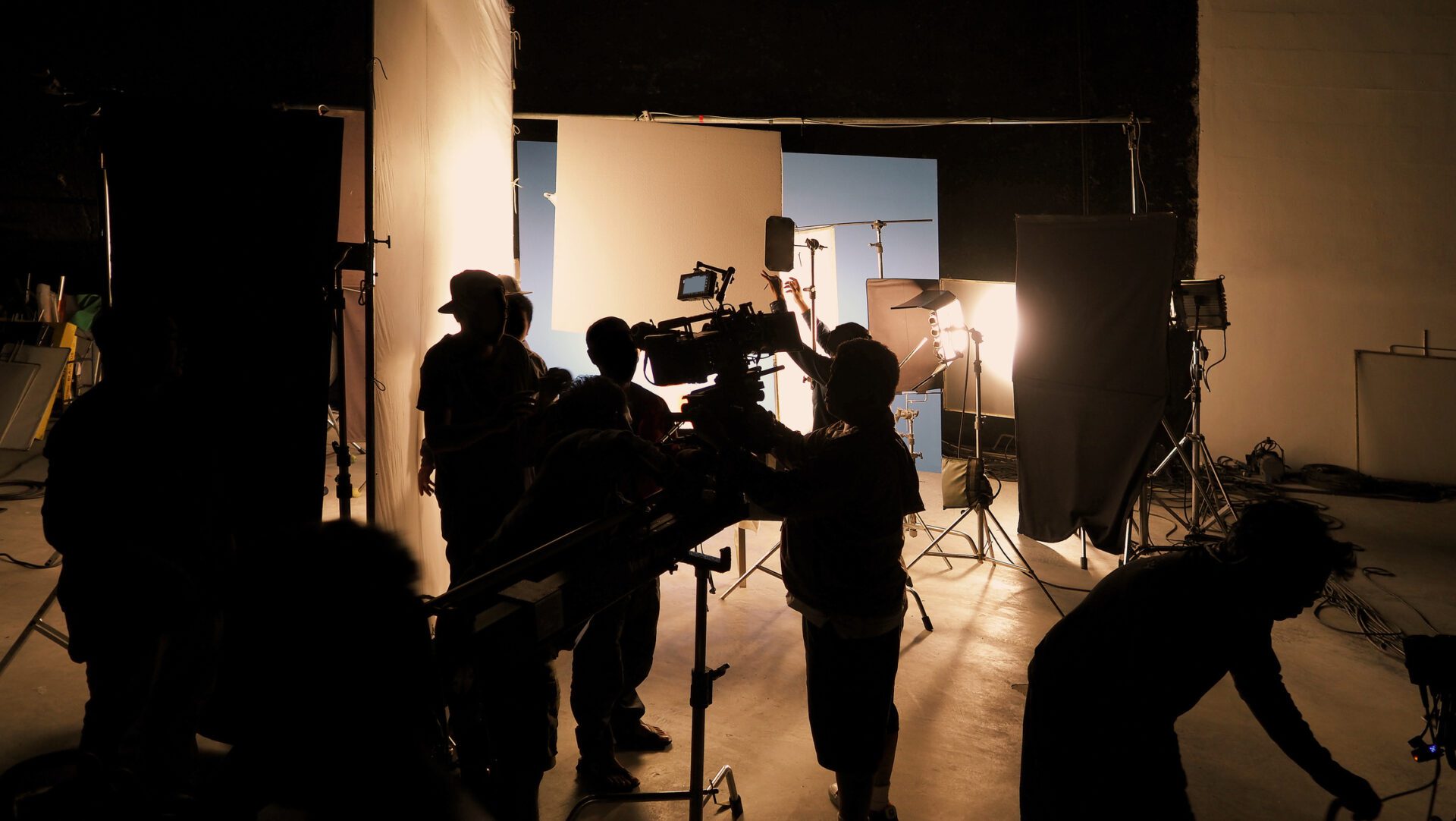 silhouettes of film crew operating camera and lighting equipment on studio set