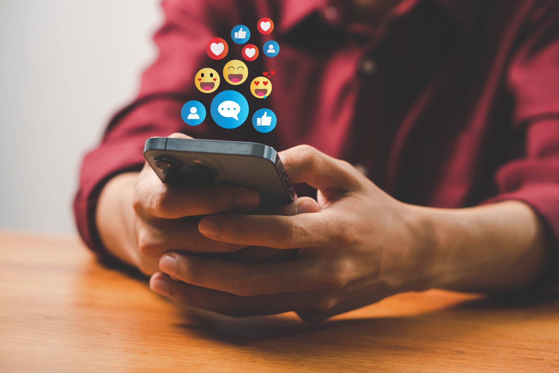man holding smartphone with floating social media reaction icons above the device
