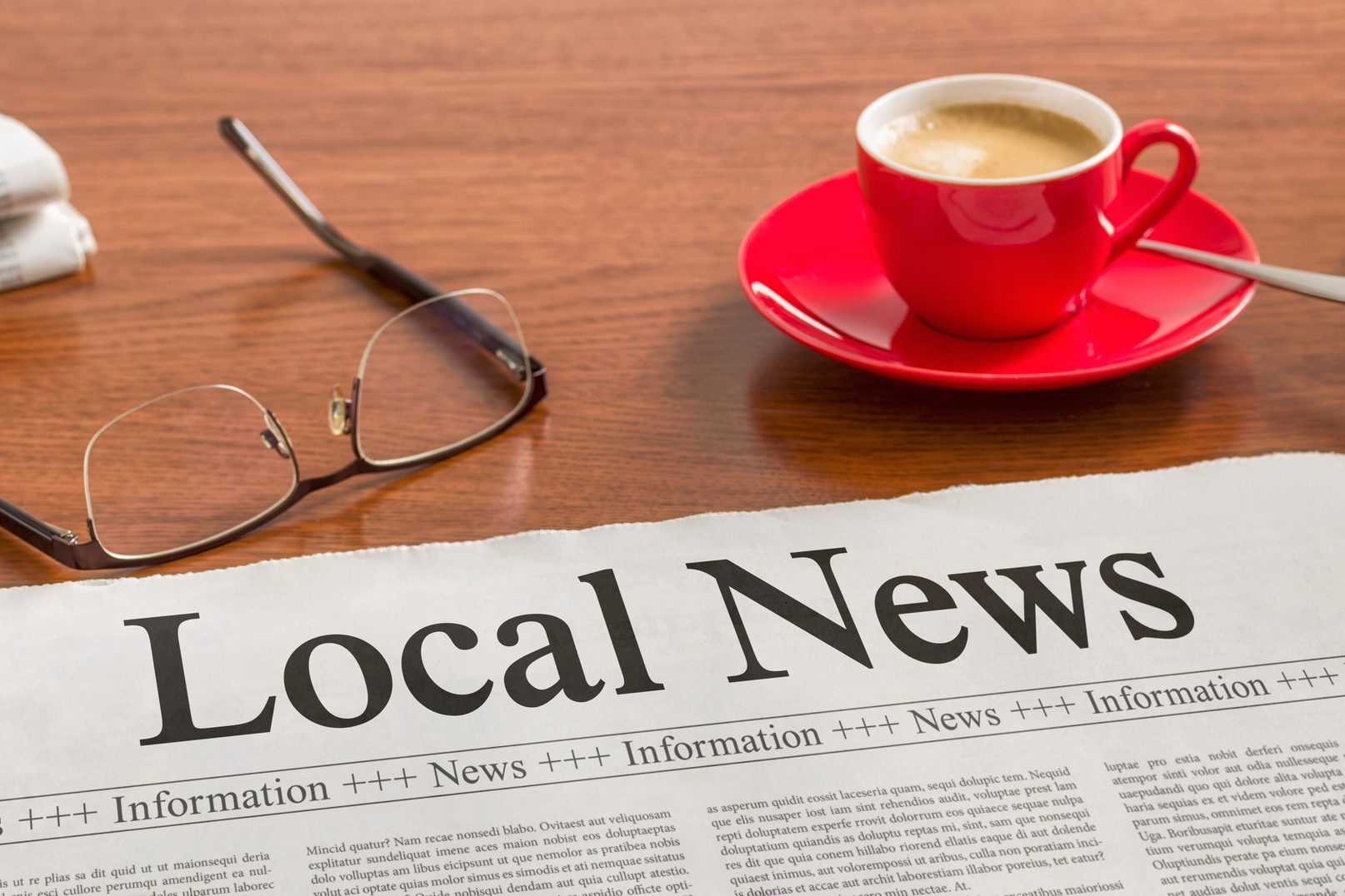 A newspaper on a wooden desk - Local News Local News newspaper on wooden desk with glasses and red coffee cup