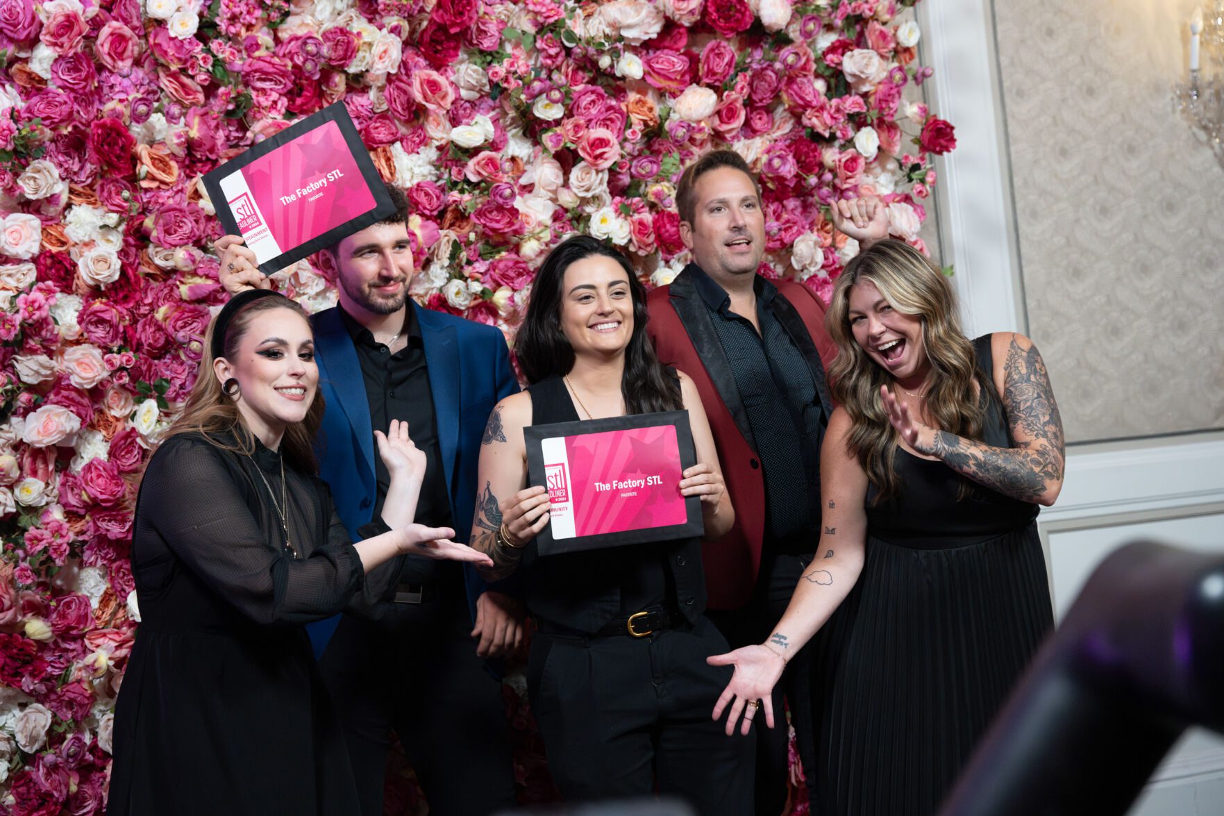 Five people posing happily with The Factory STL pink plaques in front