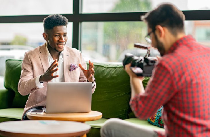 man explaining marketing strategy to camera person recording video in office setting