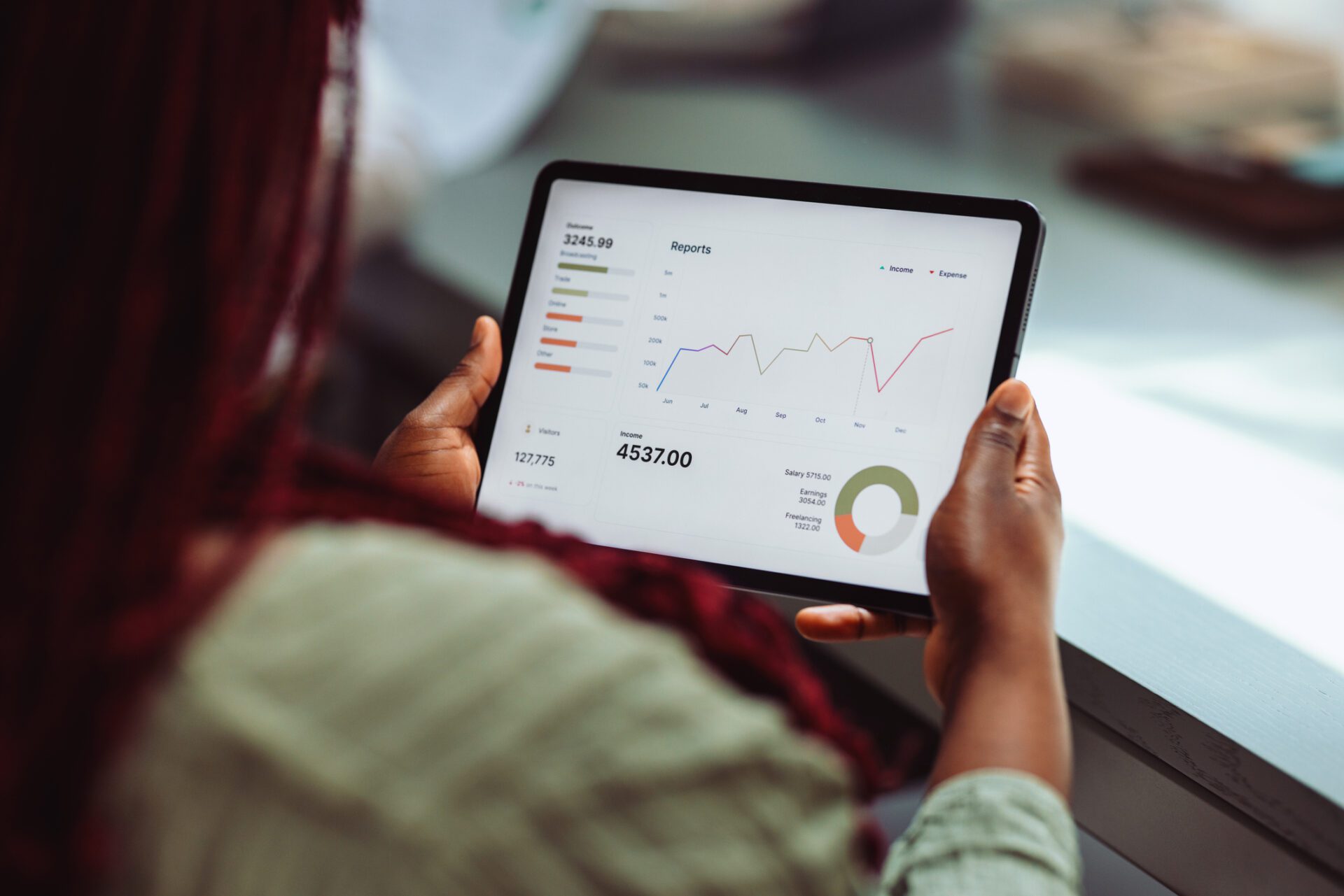 Person reviewing business analytics and financial data on a tablet, displaying charts and graphs